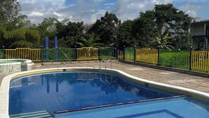 A swimming pool with a tiled deck and a fence. - Finca Hotel La Moni (Circasia)