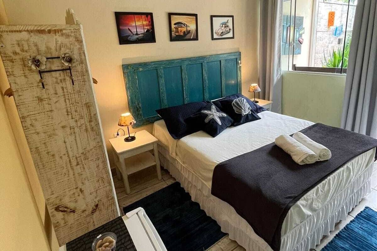 A bedroom with a bed, a nightstand, a dresser, and a window with curtains.