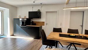 Una cocina moderna con armarios negros, una mesa de comedor de madera y una alfombra mullida.