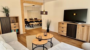 Una sala de estar moderna con un sofá, una mesa de centro, un televisor y un comedor con sillas y una mesa.