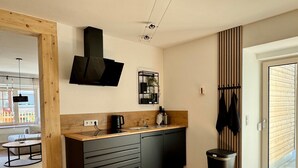 Una cocina moderna con estufa integrada, una lámpara colgante y una ventana con persianas.
