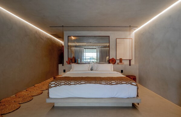 Un dormitorio moderno con una cama grande, una lámpara de techo y vistas al exterior a través de una ventana.