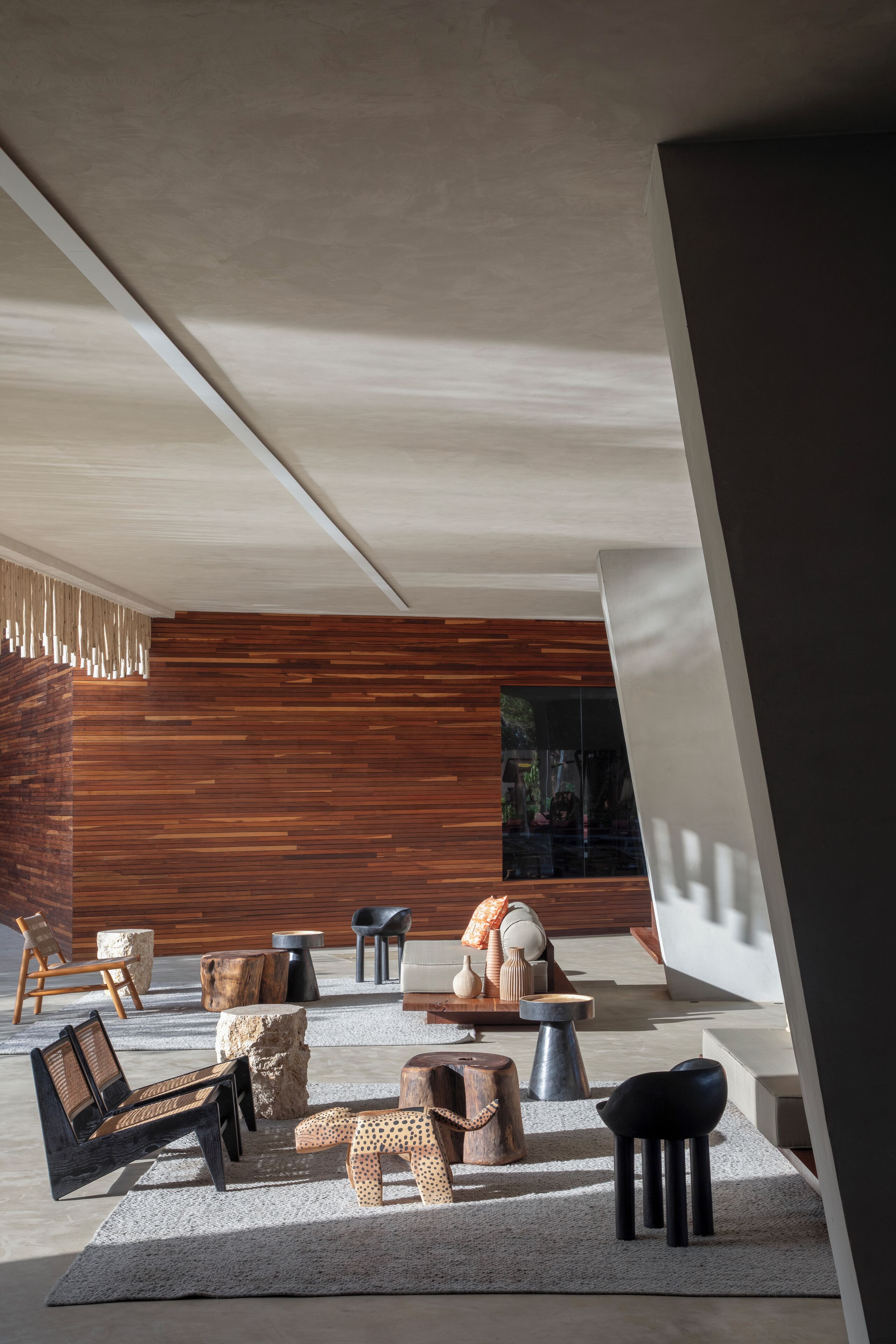 Un interior moderno con una pared de madera, un espacio de estar con un sofá, sillas y una mesa de centro.