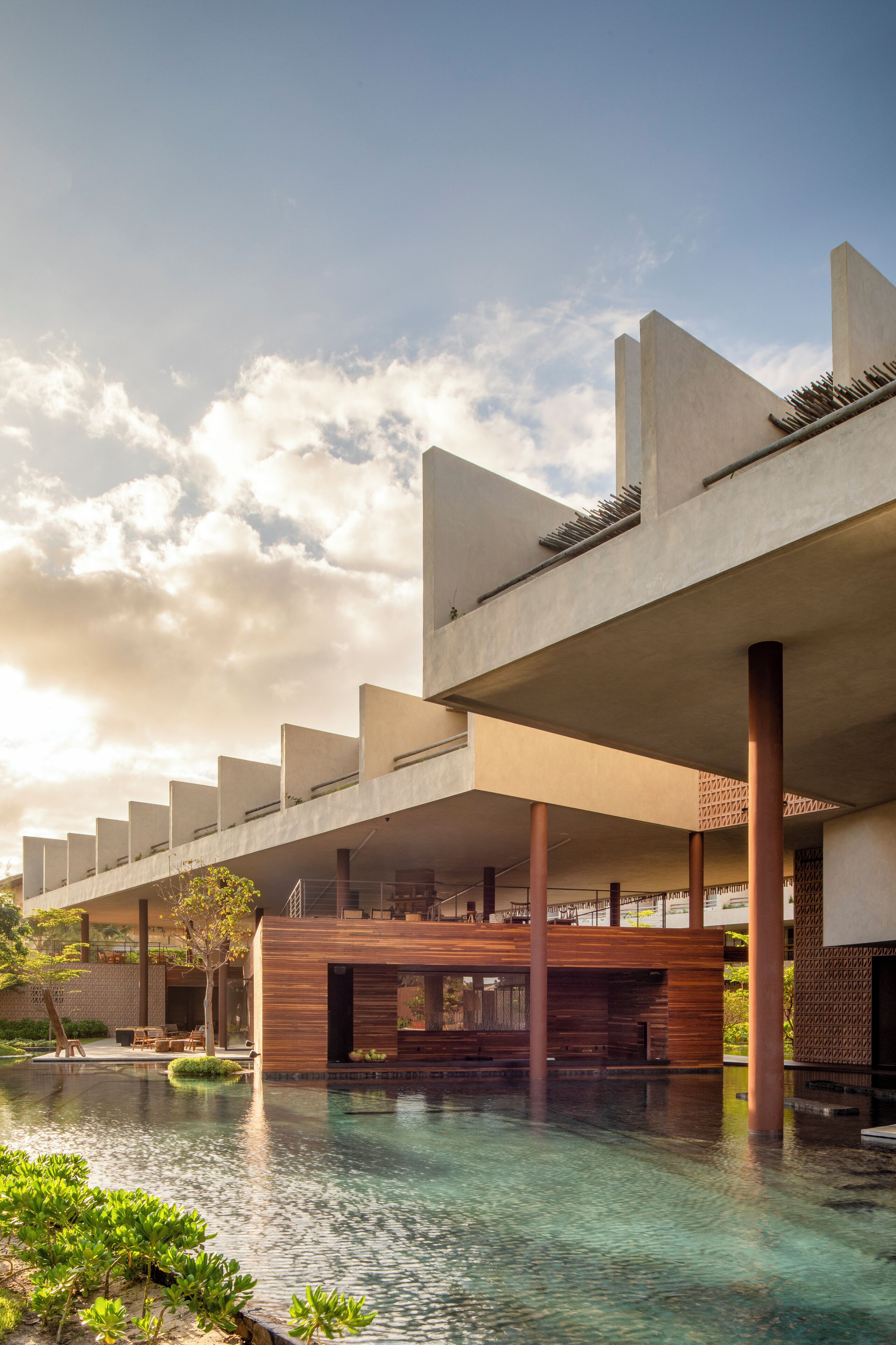 Un edificio moderno con piscina, terraza de madera y cielo despejado.