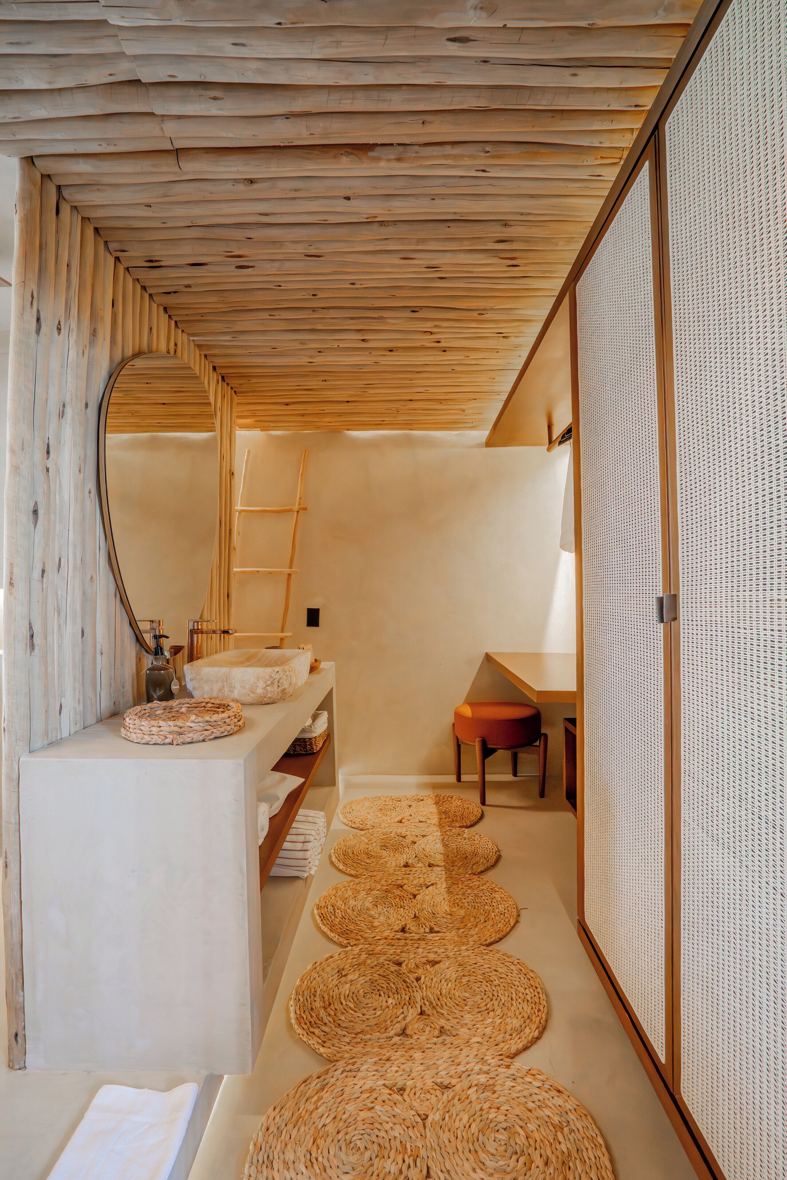 Une salle de bain moderne avec un plafond en bois, un lavabo surmonté d’un tapis tissé et un grand tapis tissé sur le sol.