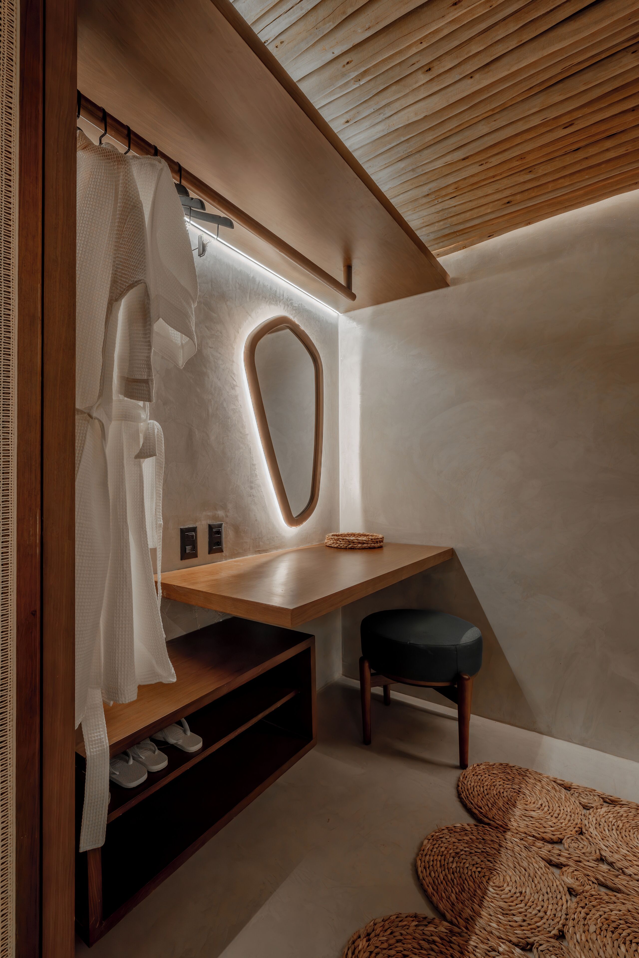 Un baño moderno con tocador de madera, un espejo y un perchero para toallas.