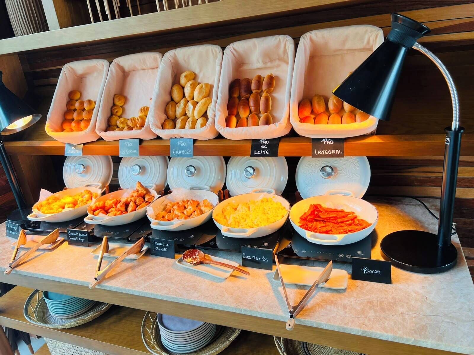 A buffet with labeled food containers and utensils.