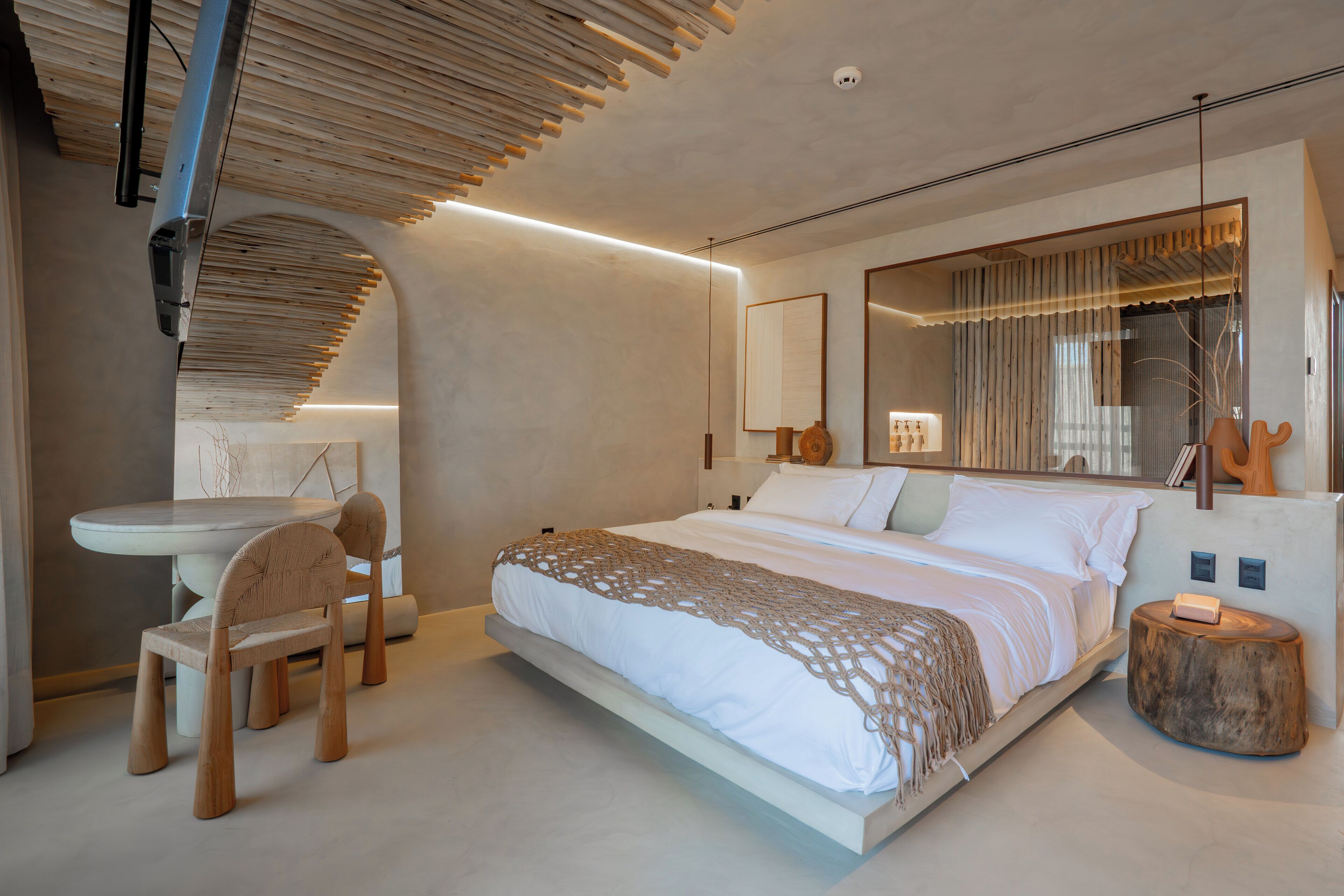 A modern bedroom with a large bed, a desk, and a chair.