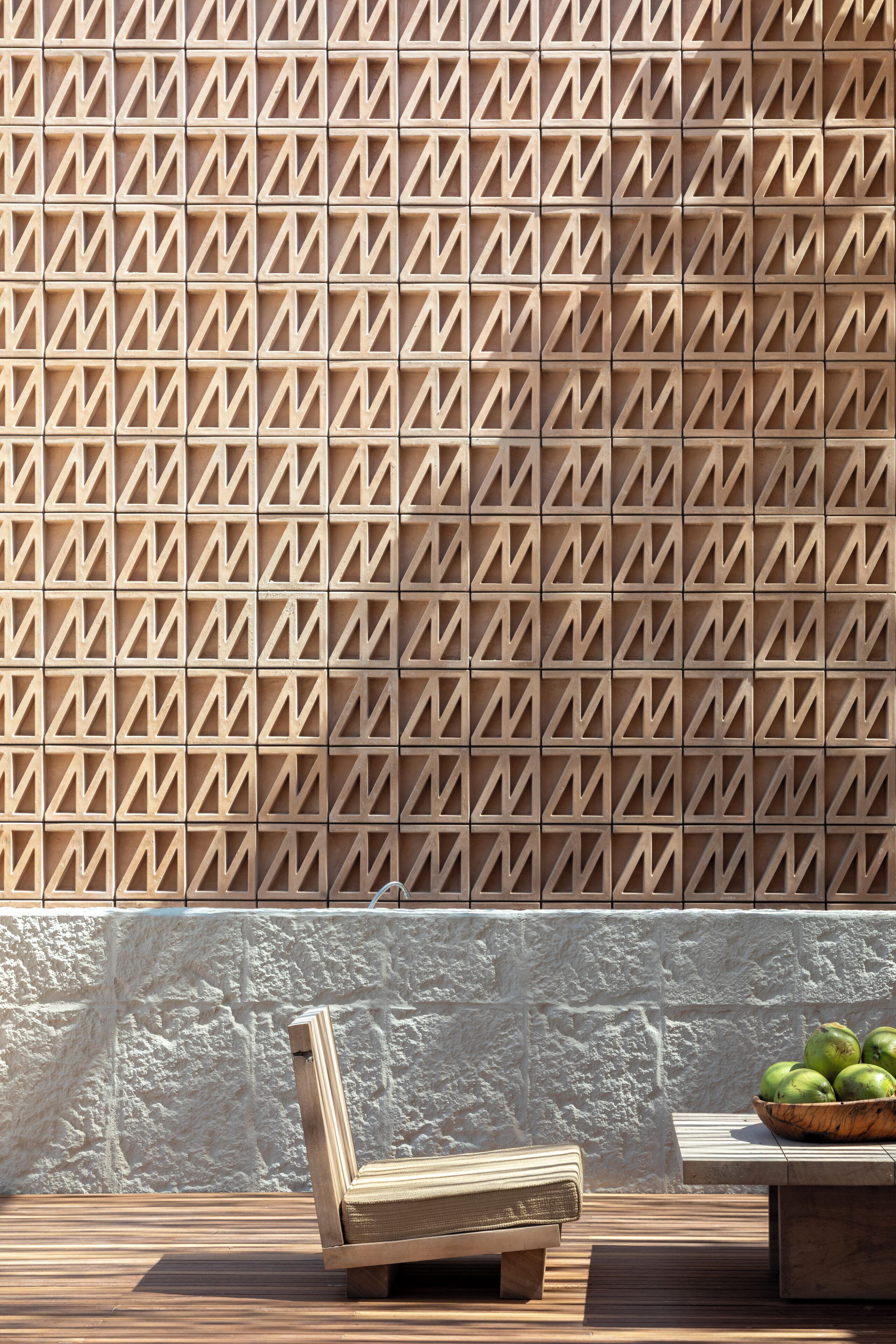 A wooden bench and a table with a bowl of fruit against a textured wall.