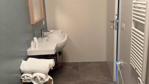 A bathroom with a sink, mirror, towel rack, and a door with a towel hanging on it. - Tremiti (Vico del Gargano)