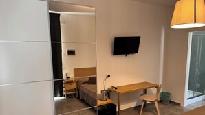 A hotel room with a bed, a desk, a chair, a TV, and a mirror. - Tremiti (Vico del Gargano)