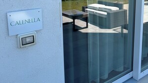 A glass door with a 'CALENELLA' sign, a glass table, and a wicker sofa. - Tremiti (Vico del Gargano)