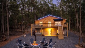 Una cabaña con terraza, mobiliario exterior y una fogata.
