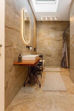 A modern bathroom with a marble wall, a wooden vanity, a large mirror, and a skylight. - Country House Dream under Walnut Trees (Nuthetal)