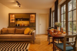 A cozy living room with a sofa, a dining table set with breakfast, and a kitchen area with cabinets and a refrigerator.