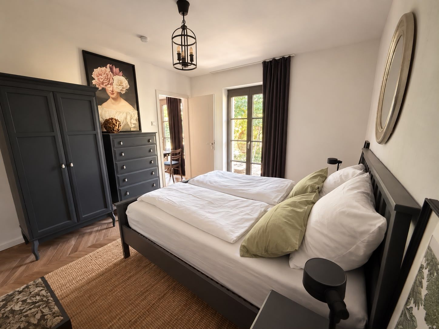Quarto com cama de casal, cômoda, cadeira e um quadro na parede.