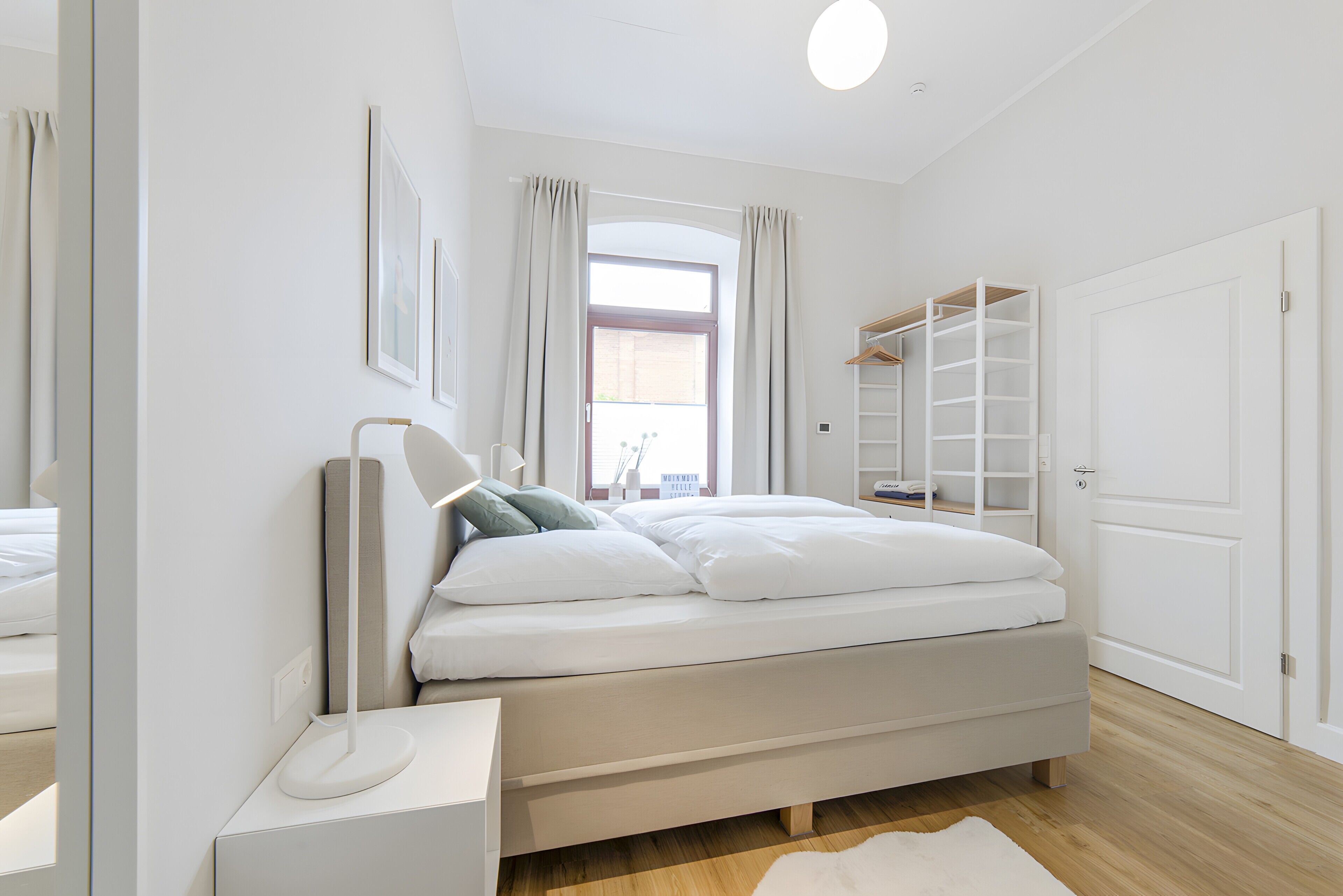 A bedroom with a bed, bedside table, lamp, and a walk-in closet.