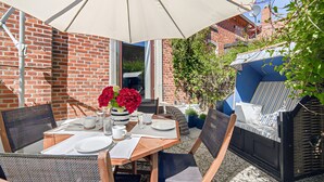 En terrasse med spiseplads, udendørs møbler og en murstensmur.