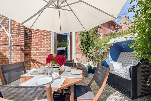 A patio with a table set for dining, outdoor seating, and a brick wall.