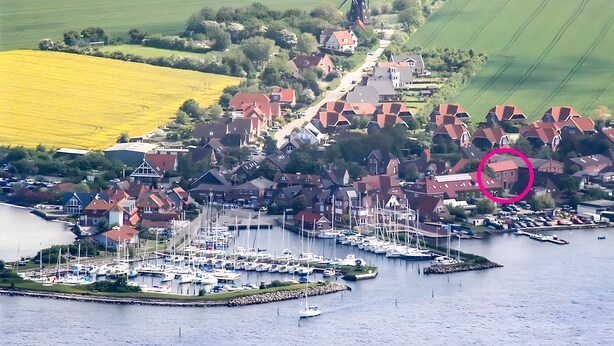 En kystlandsby med lystbådehavn, mølle og huse med røde tage.