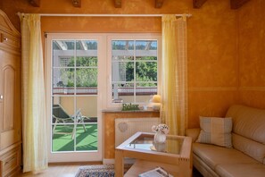 A room with a sliding glass door, a sofa, a small table with a vase, and a radiator.