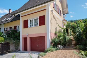 A two-story house with a garage, a stone wall, and a wooden fence.