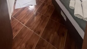Ein Schlafzimmer mit einem Bett, einem kleinen weißen Heizgerät und einem Duschbereich.