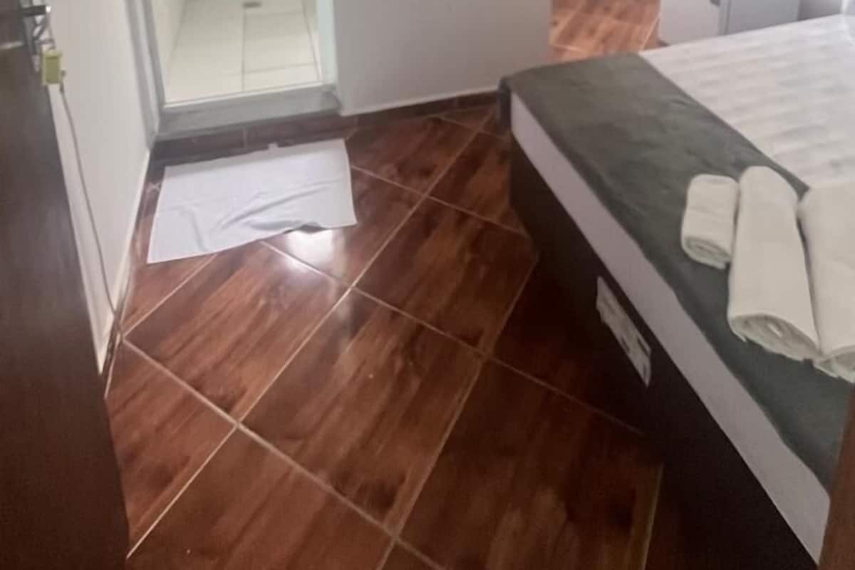 A bedroom with a bed, a small white heater, and a shower area.
