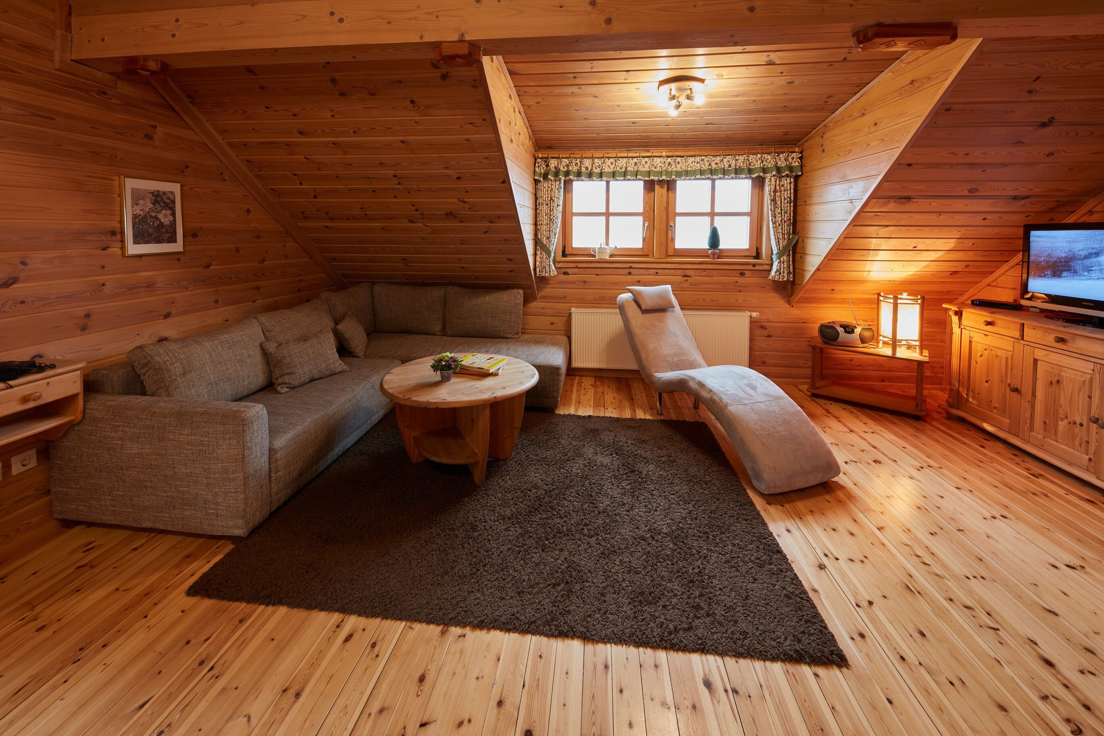 Interior acolhedor de uma cabana com sofá, poltrona e uma mesinha.
