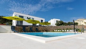 A modern pool area with a clear blue sky, a white building, and a stone wall in the background. - Apartment Nina - panoramic sea views (Slatine)