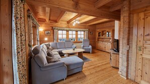 A log cabin interior with a sofa, chairs, a coffee table, and a kitchen area. - Apartment 'Daniela' with Shared Terrace, Shared Garden and Wi-Fi (Schmallenberg)