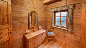 A wooden cabin bathroom with a wooden vanity, a mirror, a window with curtains, and a wooden chair. - Apartment 'Daniela' with Shared Terrace, Shared Garden and Wi-Fi (Schmallenberg)