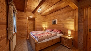 A wooden cabin bedroom with a bed, bedside tables, and a window with curtains. - Apartment 'Daniela' with Shared Terrace, Shared Garden and Wi-Fi (Schmallenberg)