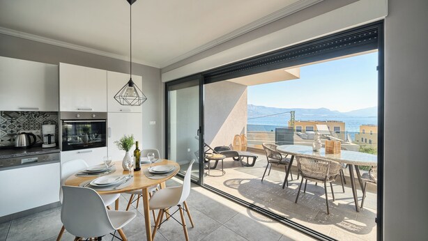 Una cocina moderna con armarios blancos y una zona de comedor con mesa y sillas.