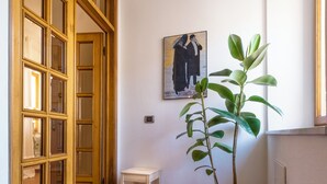 Een gang met een houten deur, een tafeltje en een bloempot.