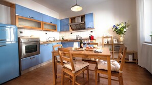Een moderne keuken met blauwe kastjes, een houten eettafel en een vaas met bloemen.