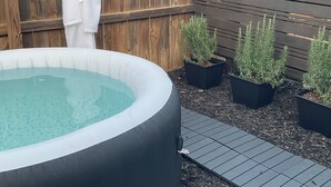 Un jacuzzi rodeado de plantas en macetas y una valla de madera.
