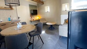 A modern kitchen with a dining area, including a round table with chairs, a sofa, and a refrigerator. - Voerendaal Family Apartment (Voerendaal)