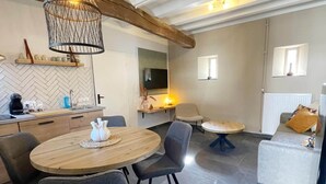 A modern kitchen with a herringbone tile backsplash, a wooden dining table with chairs, a round coffee table, and a sofa with a throw pillow. - Voerendaal Family Apartment (Voerendaal)