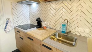 A kitchen with a herringbone tile backsplash, a wooden countertop, a stainless steel sink, a coffee maker, and a bottle of hand soap. - Voerendaal Family Apartment (Voerendaal)