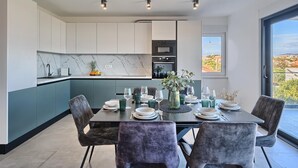 A modern kitchen with white cabinets, a marble backsplash, and a dining area with a table set for four.