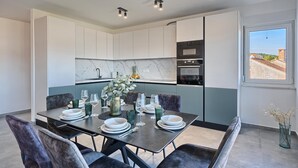 A modern kitchen with white cabinets, a marble backsplash, and built-in appliances.