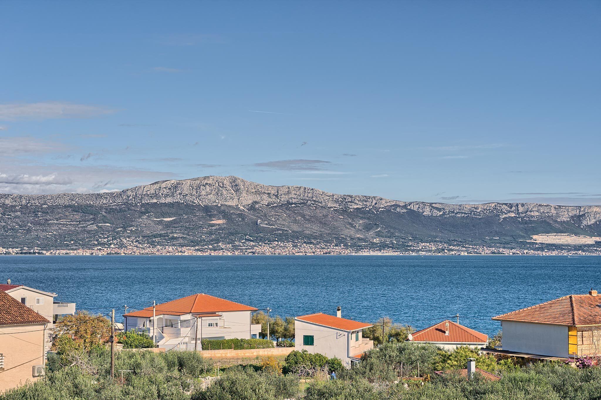 A coastal view with houses and a mountain in the background.