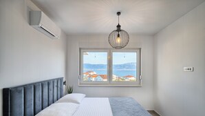 A bedroom with a bed, a window with a view, and an air conditioning unit. - Imola‘s Place - Sea-View & Pool (Slatine)