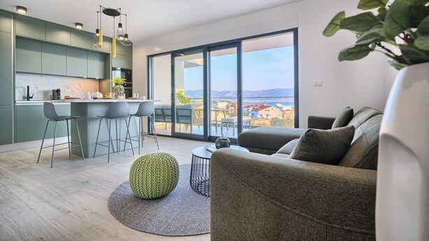 A modern living space with a kitchen, dining area, and a large window offering a city view. - Imola‘s Place - Sea-View & Pool (Slatine)