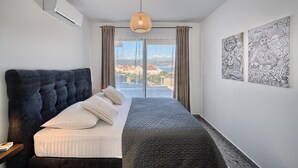 Une chambre dotée d’un grand lit, d’un climatiseur, d’un luminaire suspendu et de deux œuvres d’art accrochées au mur.