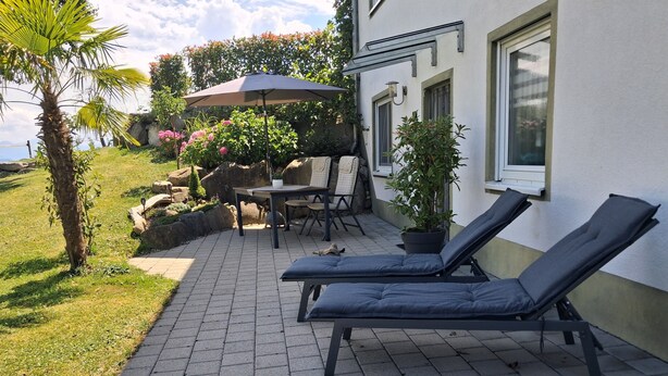 A patio with lounge chairs, a table, and a potted plant. - Apartment 'Lounge' with Mountain View, Private Terrace and Wi-Fi (Sigmarszell)