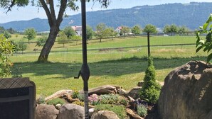 A garden with a wooden bench, large rocks, and a view of a mountainous landscape. - Apartment 'Lounge' with Mountain View, Private Terrace and Wi-Fi (Sigmarszell)