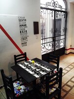Un comedor con una mesa cubierta por un mantel blanco y negro, rodeado de sillas negras. Hay una pequeña botella amarilla sobre la mesa.