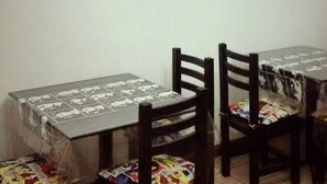 Ein Essbereich mit einem Tisch, der mit einer gemusterten Tischdecke bedeckt ist, zwei Stühlen und einer Pendelleuchte.